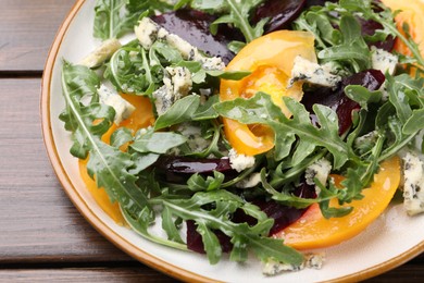 Photo of Tasty salad with arugula, blue cheese and vegetables on wooden table, closeup