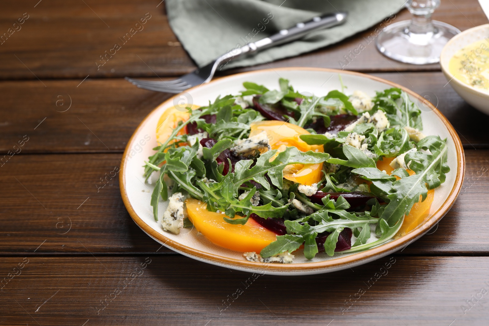 Tasty salad with arugula, blue cheese and vegetables on wooden table, closeup Photo of Tasty salad with arugula, blue cheese and vegetables on wooden table, closeup