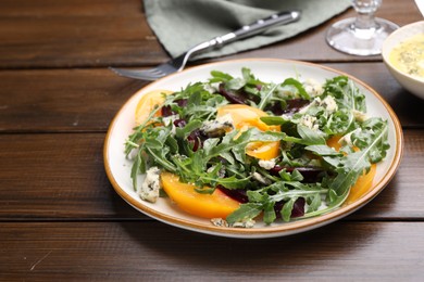 Photo of Tasty salad with arugula, blue cheese and vegetables on wooden table, closeup