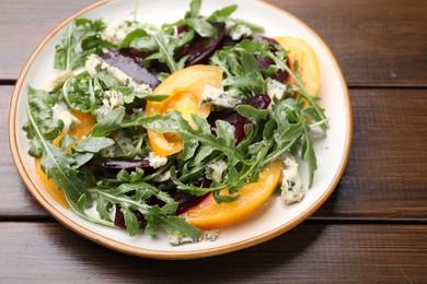 Photo of Tasty salad with arugula, blue cheese and vegetables on wooden table, closeup
