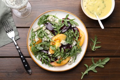 Photo of Tasty salad with arugula, blue cheese and vegetables on wooden table, flat lay