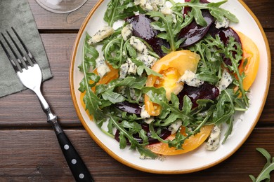 Photo of Tasty salad with arugula, blue cheese and vegetables on wooden table, flat lay