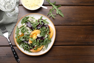 Photo of Tasty salad with arugula, blue cheese and vegetables on wooden table, flat lay. Space for text
