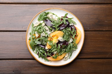 Photo of Tasty salad with arugula, blue cheese and vegetables on wooden table, top view