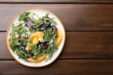 Photo of Tasty salad with arugula, blue cheese and vegetables on wooden table, top view. Space for text