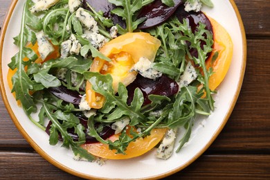 Photo of Tasty salad with arugula, blue cheese and vegetables on wooden table, top view