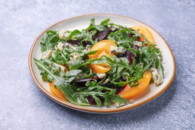 Photo of Tasty salad with arugula, blue cheese and vegetables on grey textured table, closeup