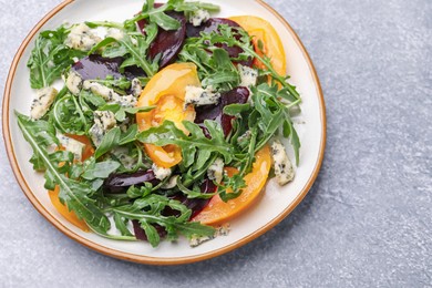Photo of Tasty salad with arugula, blue cheese and vegetables on grey textured table, above view