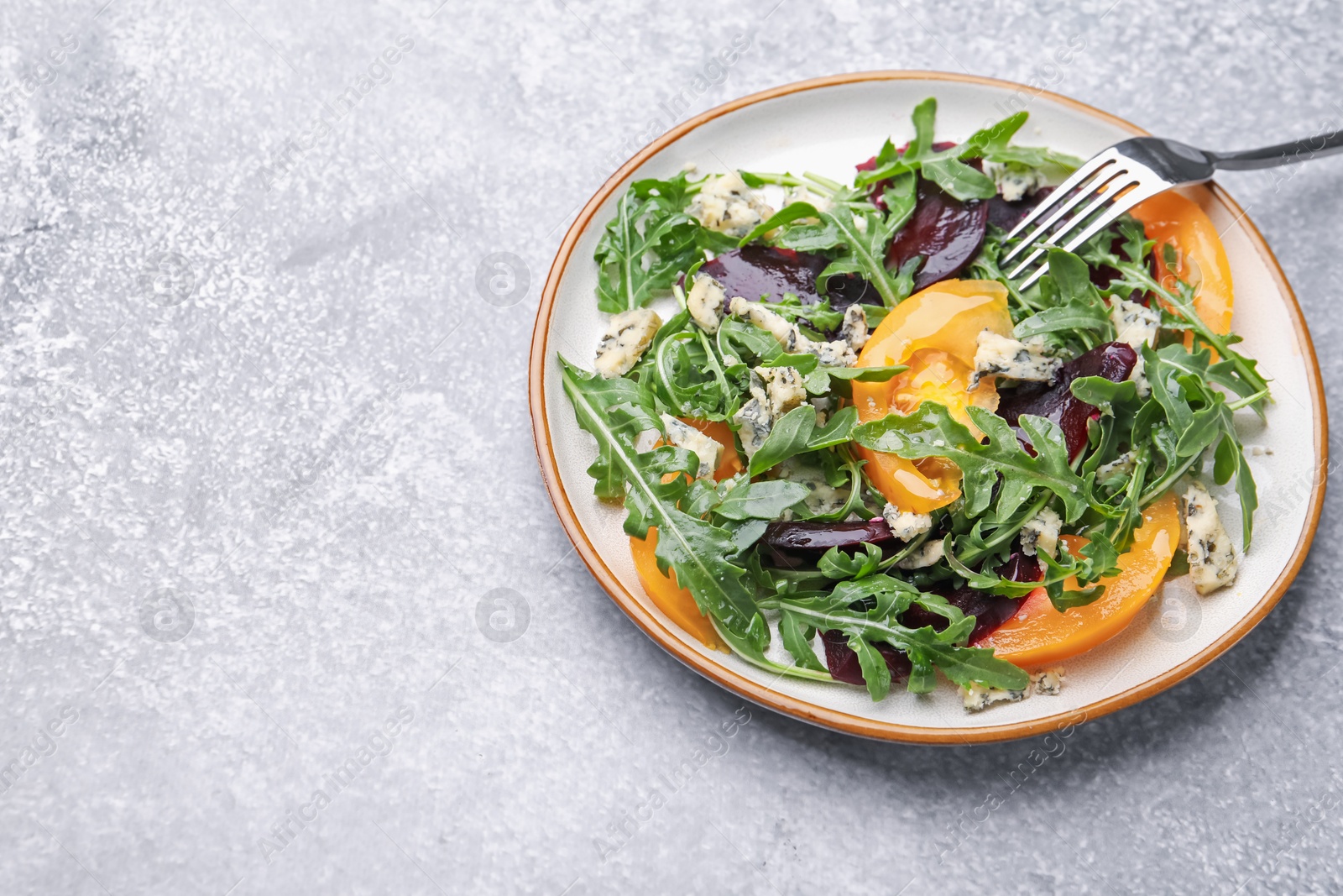 Tasty salad with arugula, blue cheese and vegetables on grey textured table. Space for text Photo of Tasty salad with arugula, blue cheese and vegetables on grey textured table. Space for text