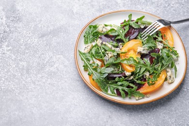 Photo of Tasty salad with arugula, blue cheese and vegetables on grey textured table. Space for text