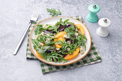 Photo of Tasty salad with arugula, blue cheese and vegetables on grey textured table