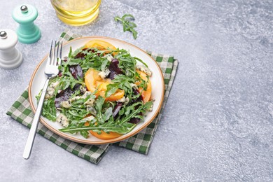 Photo of Tasty salad with arugula, blue cheese and vegetables on grey textured table. Space for text