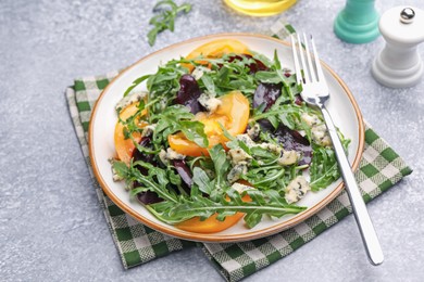 Photo of Tasty salad with arugula, blue cheese and vegetables on grey textured table, closeup