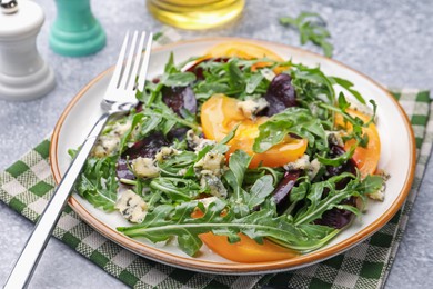 Photo of Tasty salad with arugula, blue cheese and vegetables on grey textured table, closeup