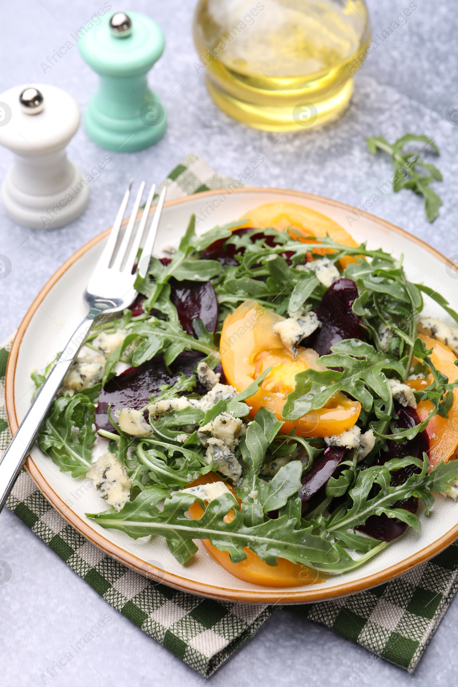 Tasty salad with arugula, blue cheese and vegetables on grey textured table, closeup Photo of Tasty salad with arugula, blue cheese and vegetables on grey textured table, closeup