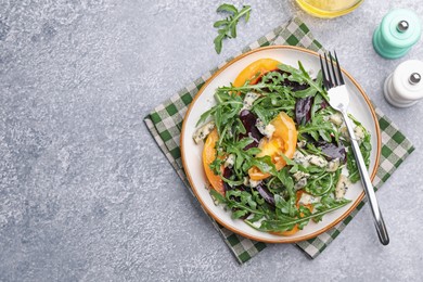 Photo of Tasty salad with arugula, blue cheese and vegetables on grey textured table, flat lay. Space for text