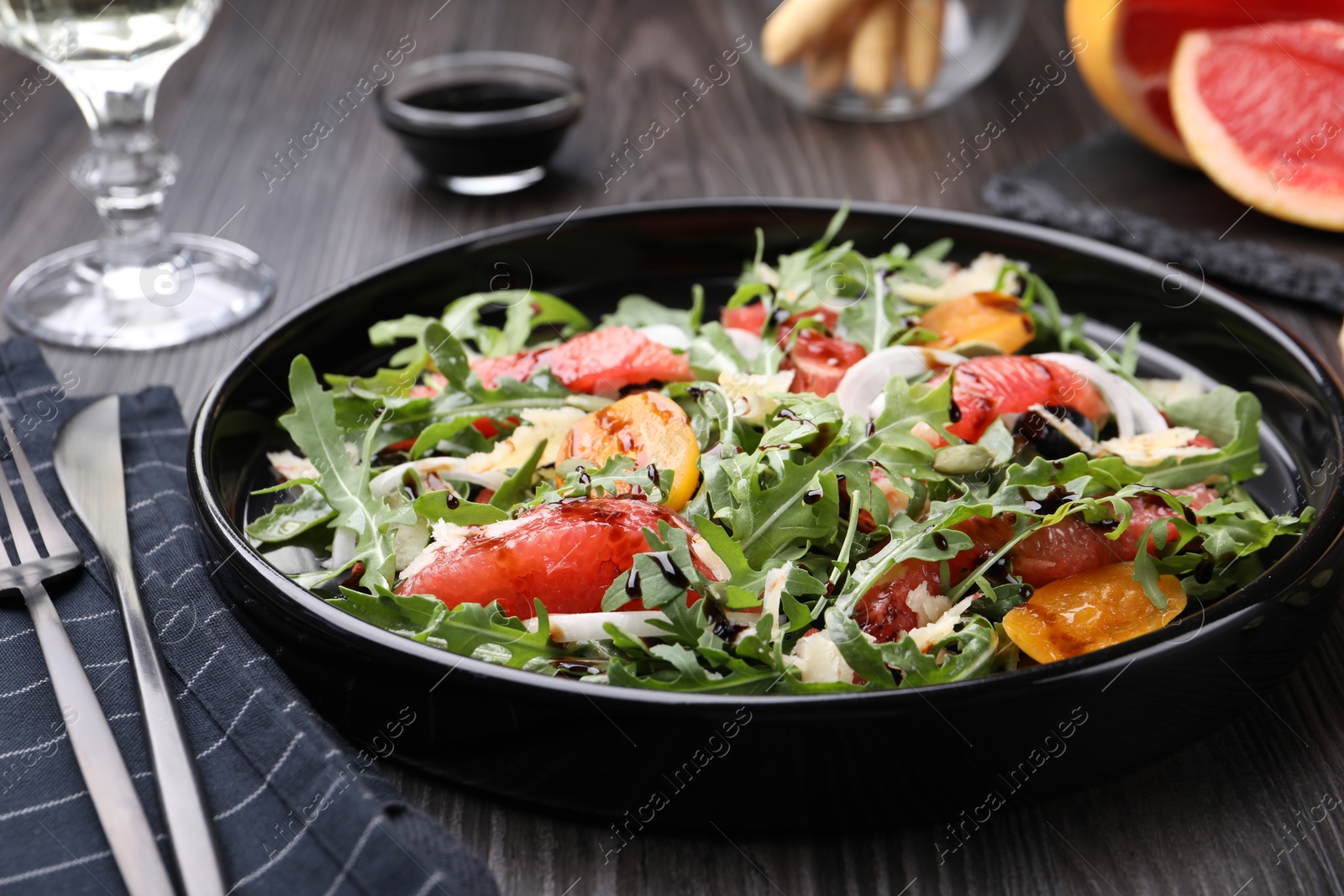 Tasty salad with arugula, cheese, grapefruit, vegetable and balsamic sauce on dark wooden table, closeup Photo of Tasty salad with arugula, cheese, grapefruit, vegetable and balsamic sauce on dark wooden table, closeup