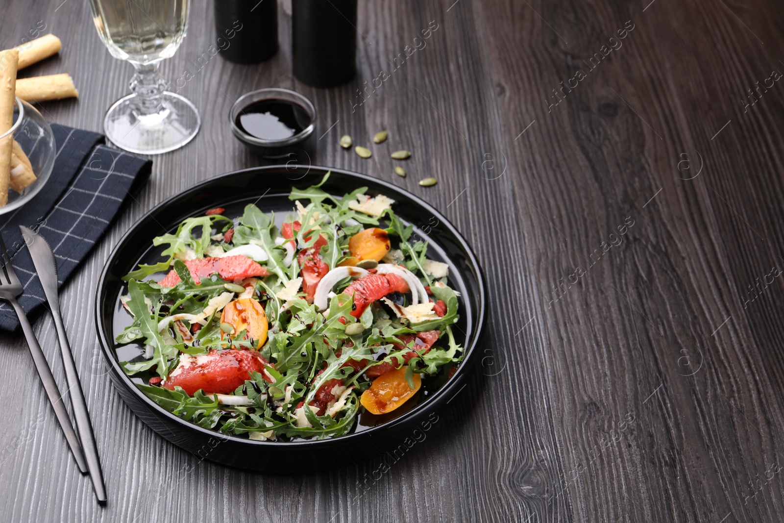 Tasty salad with arugula, cheese, grapefruit, vegetable and balsamic sauce on dark wooden table, closeup. Space for text Photo of Tasty salad with arugula, cheese, grapefruit, vegetable and balsamic sauce on dark wooden table, closeup. Space for text