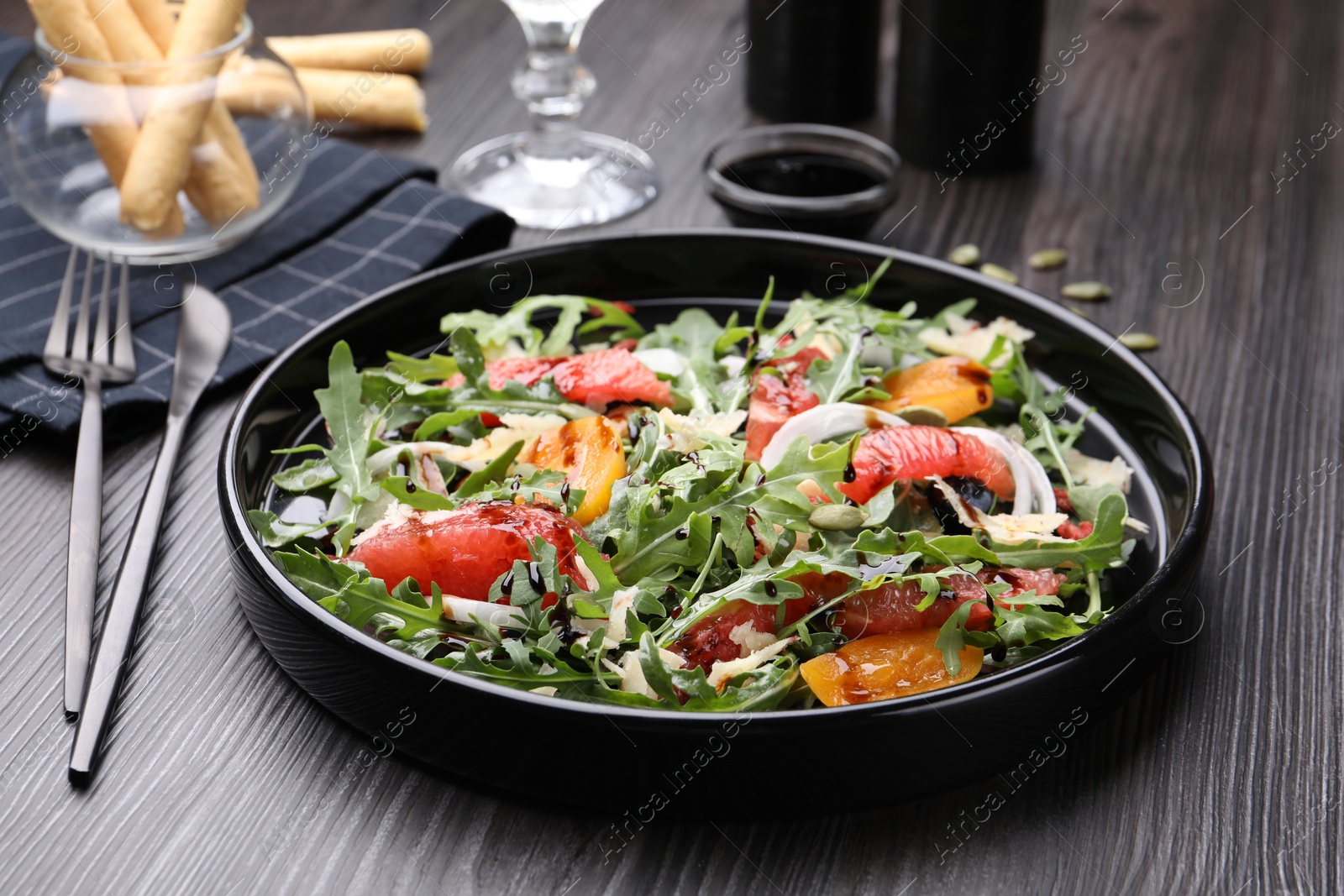 Tasty salad with arugula, cheese, grapefruit, vegetable and balsamic sauce on dark wooden table, closeup Photo of Tasty salad with arugula, cheese, grapefruit, vegetable and balsamic sauce on dark wooden table, closeup