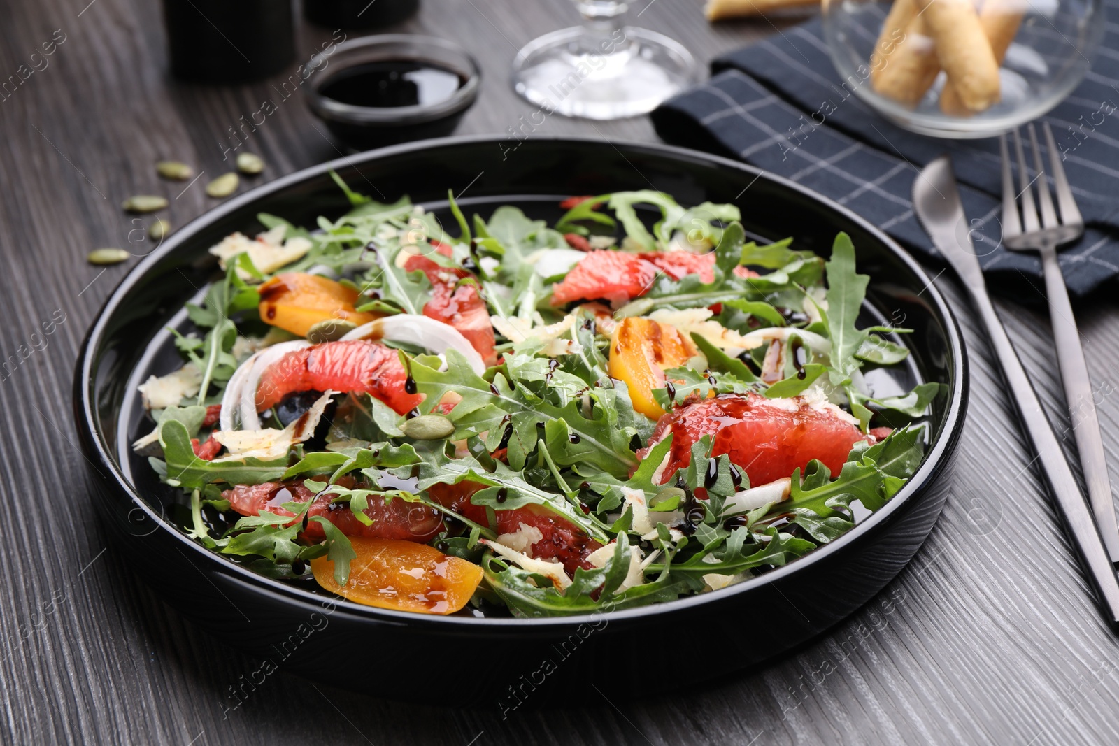 Tasty salad with arugula, cheese, grapefruit, vegetable and balsamic sauce on dark wooden table, closeup Photo of Tasty salad with arugula, cheese, grapefruit, vegetable and balsamic sauce on dark wooden table, closeup