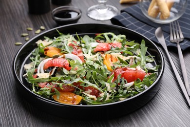 Photo of Tasty salad with arugula, cheese, grapefruit, vegetable and balsamic sauce on dark wooden table, closeup