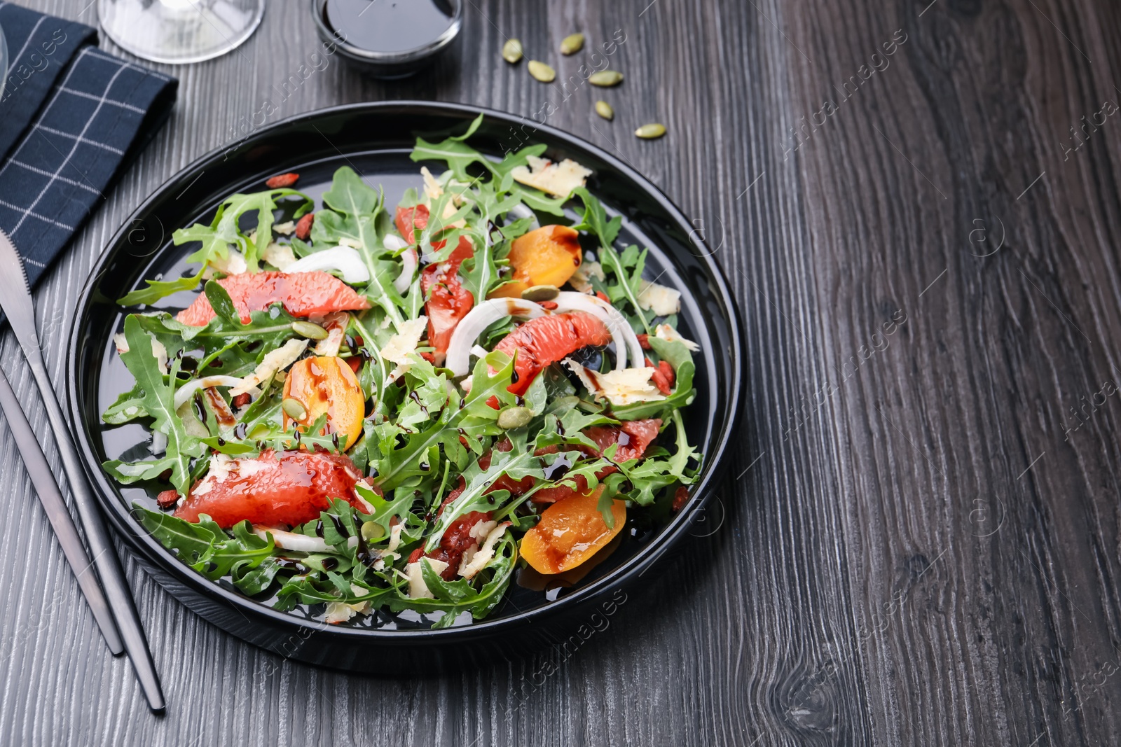 Tasty salad with arugula, cheese, grapefruit, vegetable and balsamic sauce on dark wooden table, closeup. Space for text Photo of Tasty salad with arugula, cheese, grapefruit, vegetable and balsamic sauce on dark wooden table, closeup. Space for text