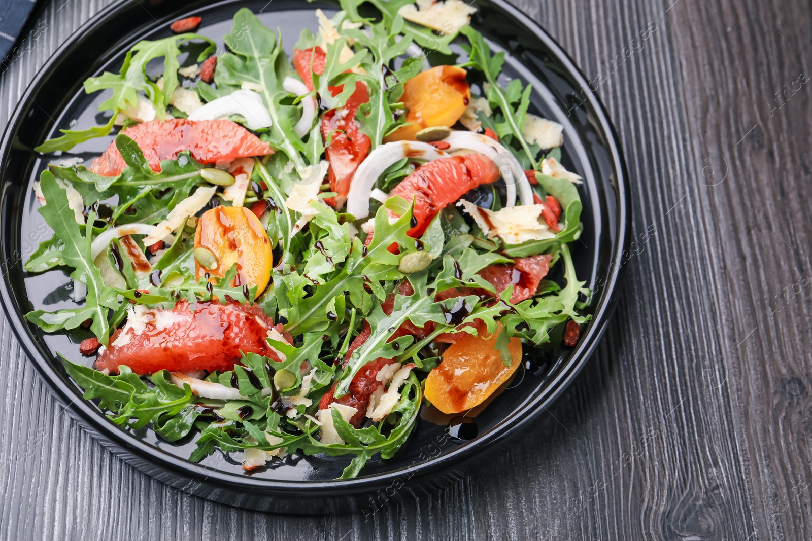 Tasty salad with arugula, cheese, grapefruit, vegetable and balsamic sauce on dark wooden table, above view Photo of Tasty salad with arugula, cheese, grapefruit, vegetable and balsamic sauce on dark wooden table, above view