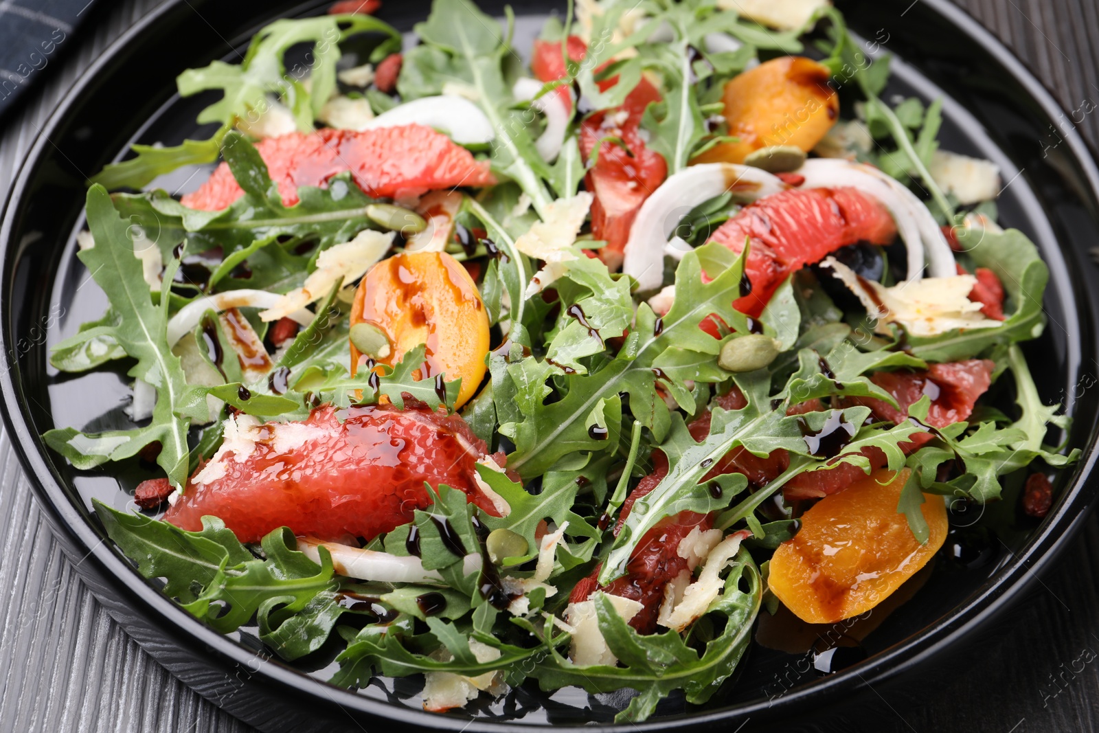 Tasty salad with arugula, cheese, grapefruit, vegetable and balsamic sauce on dark wooden table, closeup Photo of Tasty salad with arugula, cheese, grapefruit, vegetable and balsamic sauce on dark wooden table, closeup