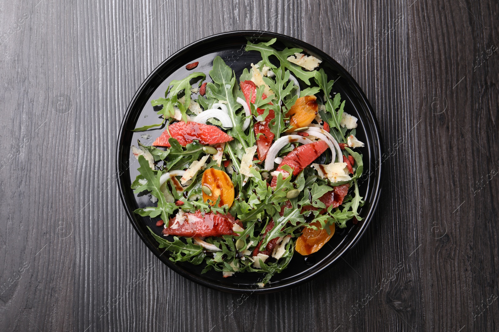 Tasty salad with arugula, cheese, grapefruit, vegetable and balsamic sauce on dark wooden table, top view Photo of Tasty salad with arugula, cheese, grapefruit, vegetable and balsamic sauce on dark wooden table, top view