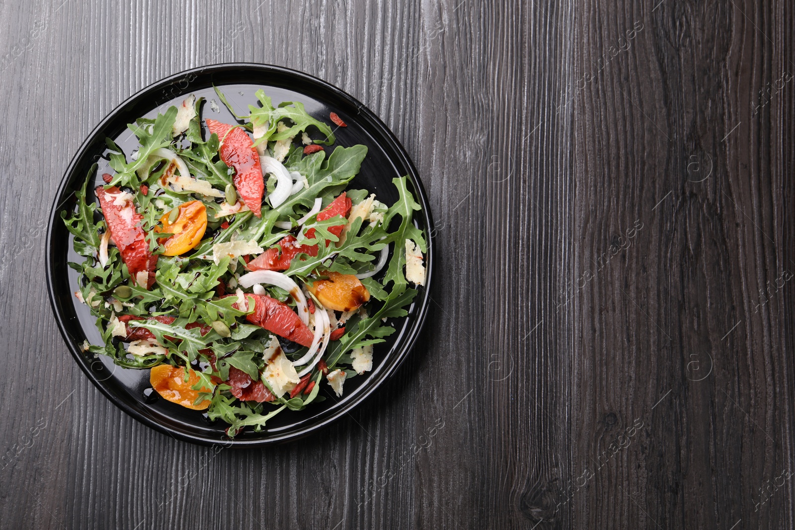 Tasty salad with arugula, cheese, grapefruit, vegetable and balsamic sauce on dark wooden table, top view. Space for text Photo of Tasty salad with arugula, cheese, grapefruit, vegetable and balsamic sauce on dark wooden table, top view. Space for text