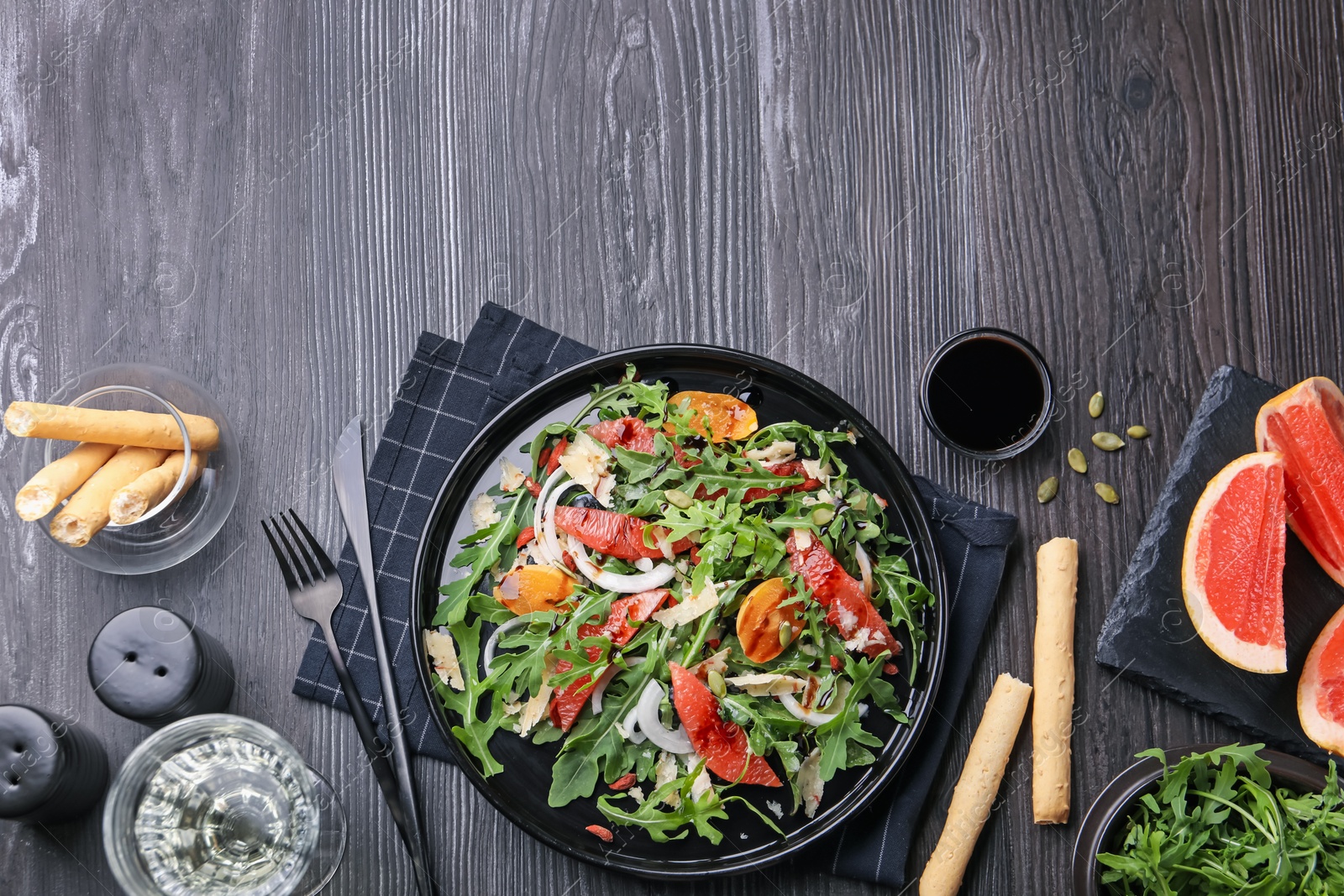 Tasty salad with arugula, cheese, grapefruit, vegetable and balsamic sauce served on dark wooden table, flat lay. Space for text Photo of Tasty salad with arugula, cheese, grapefruit, vegetable and balsamic sauce served on dark wooden table, flat lay. Space for text