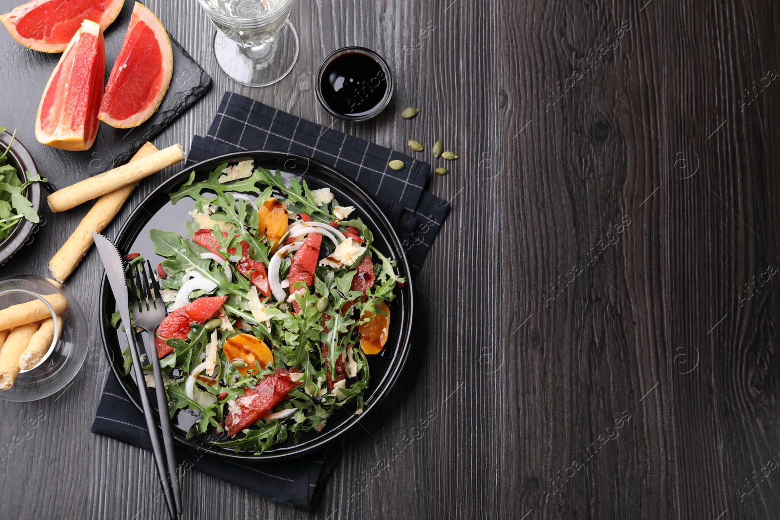 Tasty salad with arugula, cheese, grapefruit, vegetable and balsamic sauce served on dark wooden table, flat lay. Space for text Photo of Tasty salad with arugula, cheese, grapefruit, vegetable and balsamic sauce served on dark wooden table, flat lay. Space for text