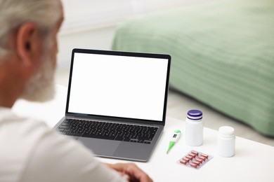 Photo of Senior man having online consultation with doctor via laptop at table indoors, closeup