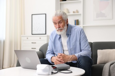 Photo of Senior man having online consultation with doctor via laptop at home