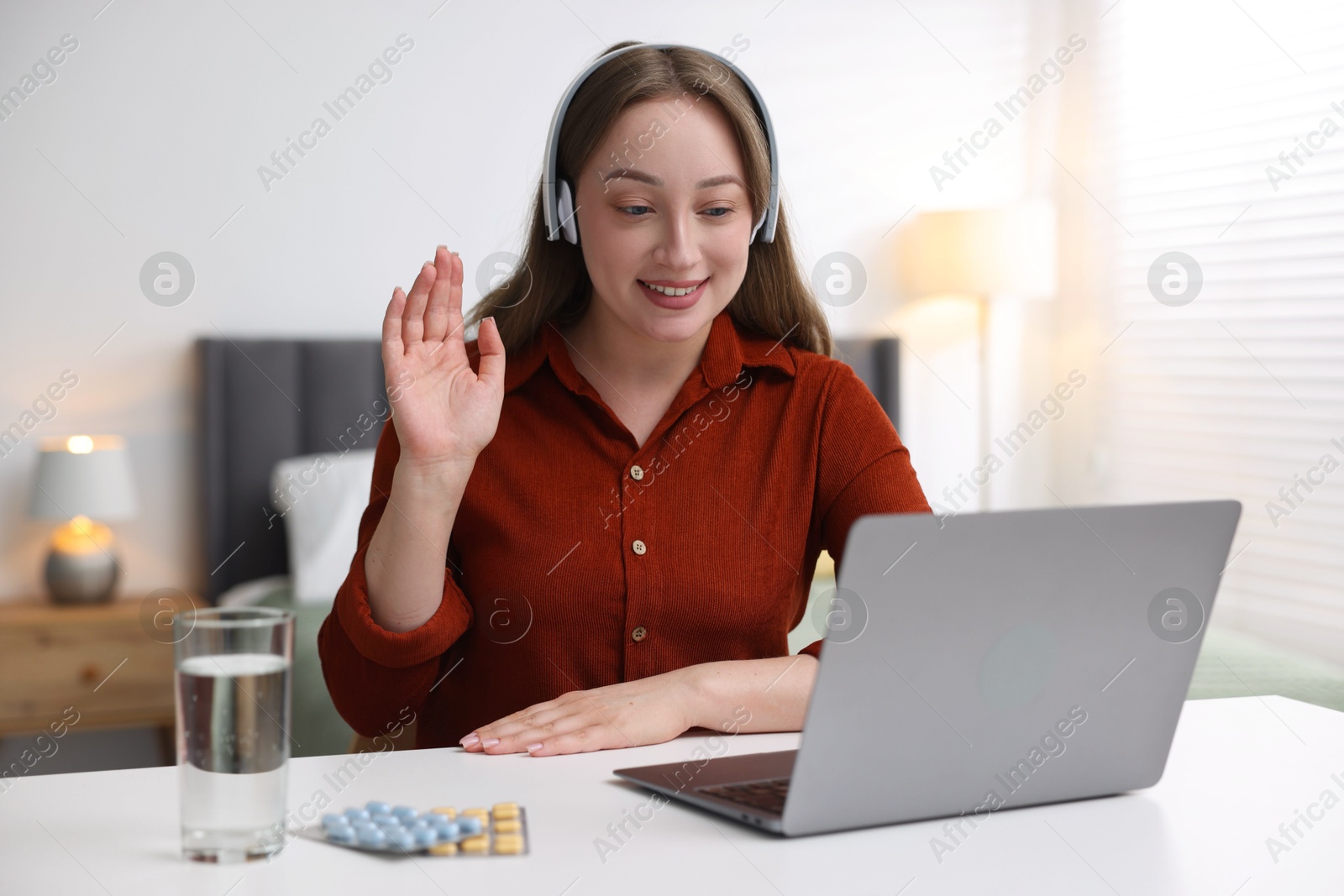 Woman in headphones having online consultation with doctor via laptop at table indoors Photo of Woman in headphones having online consultation with doctor via laptop at table indoors