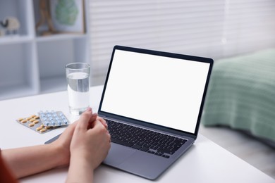 Photo of Woman having online consultation with doctor via laptop at table indoors, closeup