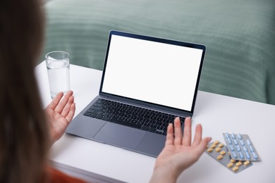 Photo of Woman having online consultation with doctor via laptop at table indoors, closeup