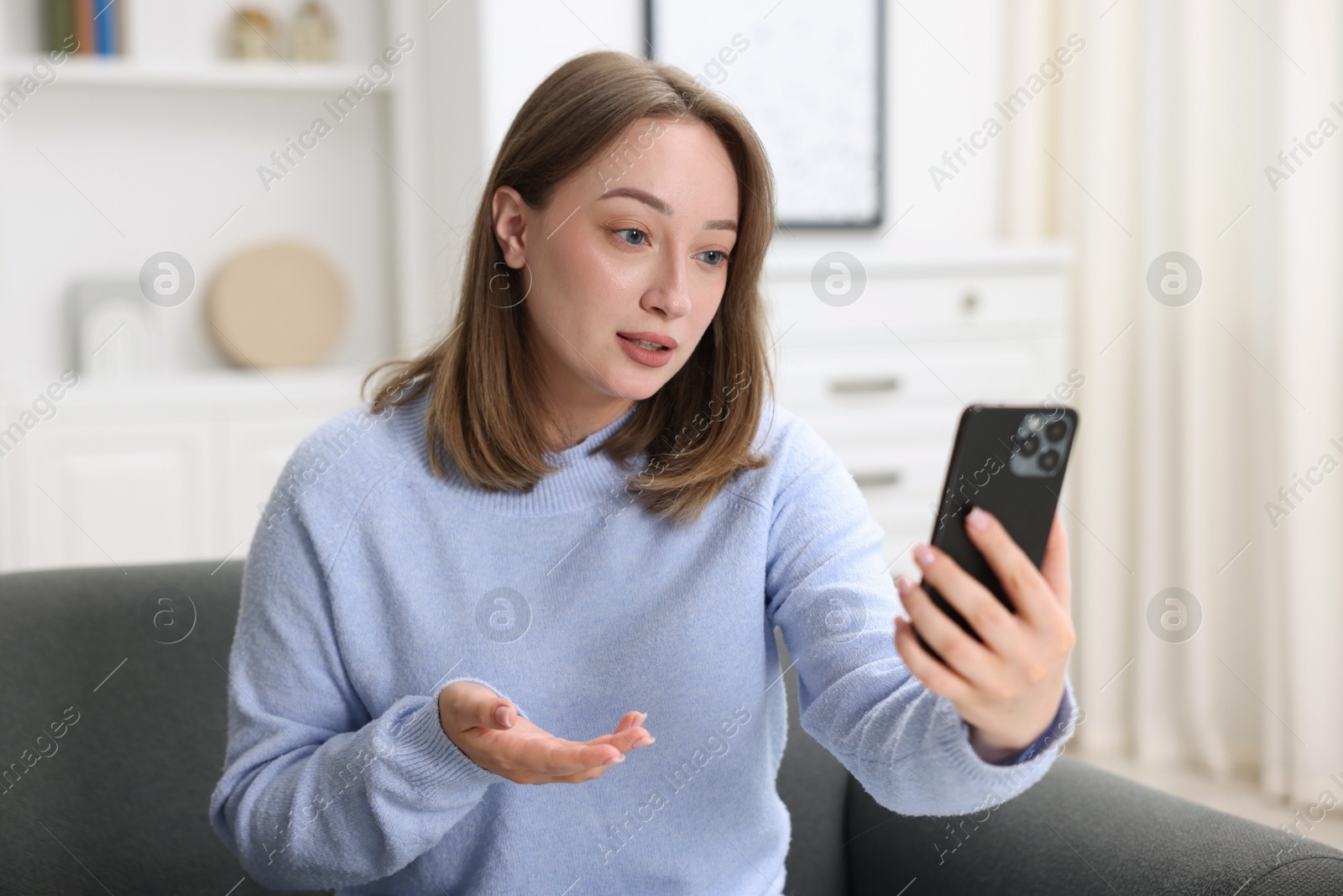 Woman having online consultation with doctor via smartphone at home Photo of Woman having online consultation with doctor via smartphone at home
