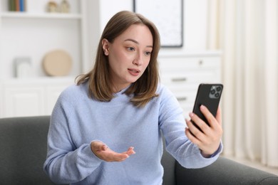Photo of Woman having online consultation with doctor via smartphone at home