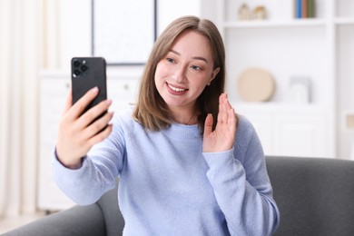 Photo of Woman having online consultation with doctor via smartphone at home