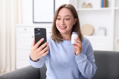 Photo of Woman with pills having online consultation with doctor via smartphone at home