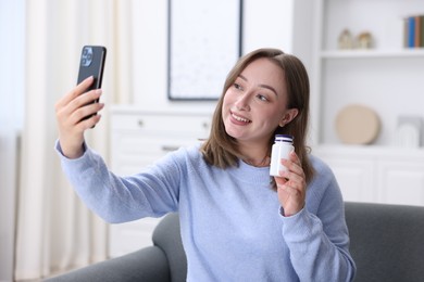Photo of Woman with pills having online consultation with doctor via smartphone at home