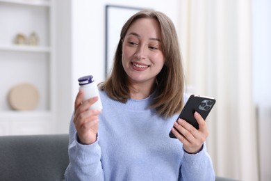 Photo of Woman with pills having online consultation with doctor via smartphone at home