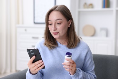 Photo of Woman with pills having online consultation with doctor via smartphone at home