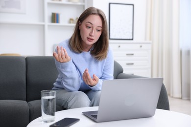 Photo of Woman having online consultation with doctor via laptop at home