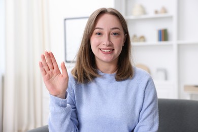 Photo of Portrait of happy woman waving at home. Online medical consultation