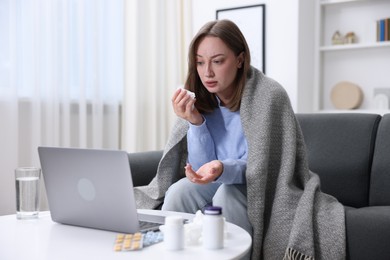 Photo of Sick woman with paper tissue having online consultation with doctor via laptop at home