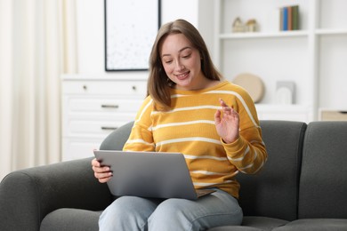 Photo of Woman having online consultation with doctor via laptop on sofa at home