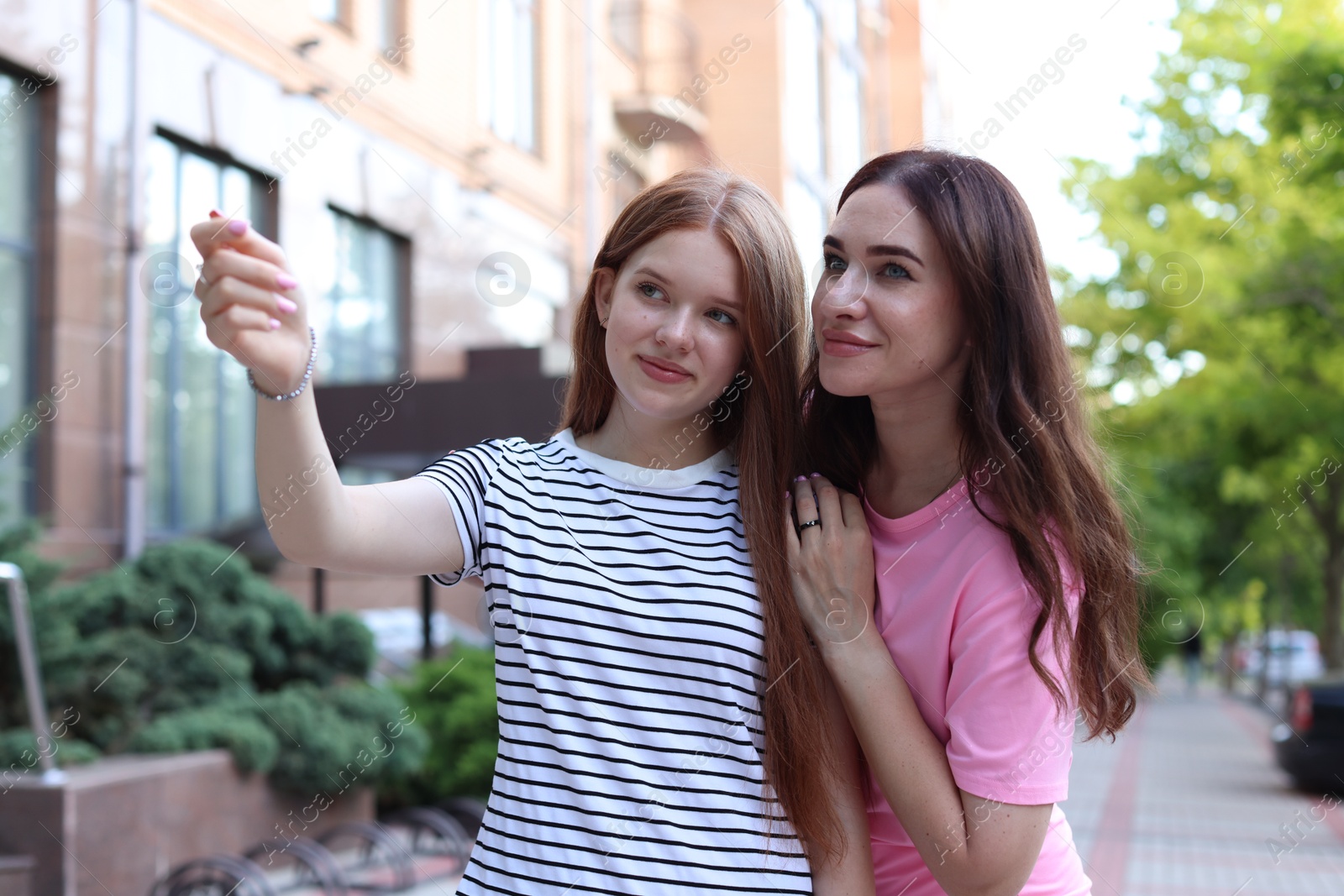 Teenage daughter showing something to her mother on city street Photo of Teenage daughter showing something to her mother on city street