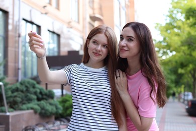 Photo of Teenage daughter showing something to her mother on city street